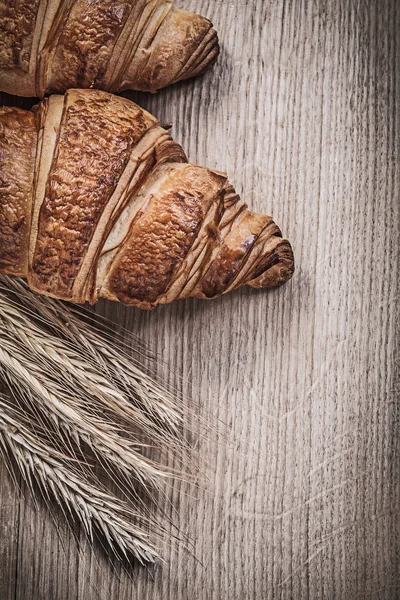 Composição de trigo dourado espigas de centeio croissants doces em madeira — Fotografia de Stock