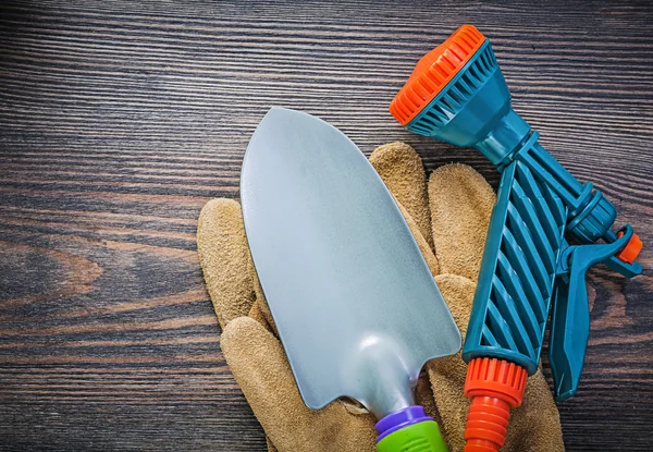 Tubo da giardino ugello guanti protettivi pala a mano su tavola di legno — Foto Stock