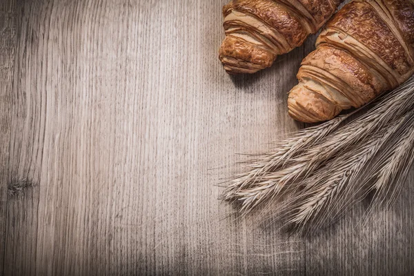 Croissants de espigas de centeno de trigo sobre tabla de madera —  Fotos de Stock