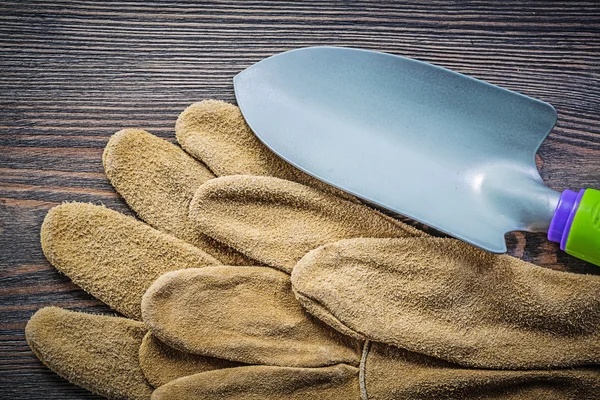 Shovel pair of safety gloves on wooden board directly above gard — Stock Photo, Image