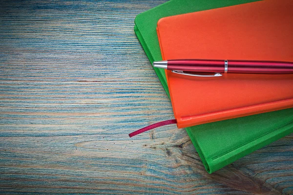 Bloc de notas cerrado pluma biro en concepto de educación tablero de madera — Foto de Stock