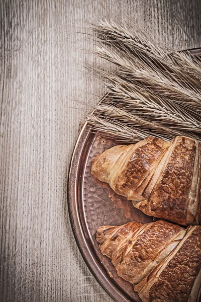 Orecchie di segale di grano maturo vassoio in ottone dolce croissant su tavola di legno — Foto Stock