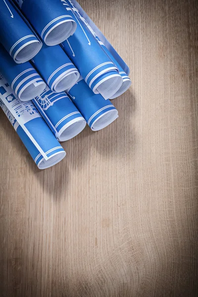 Tas de bleu enroulé plans de construction sur planche de bois — Photo