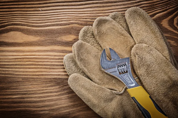 Protective gloves adjustable spanner on wooden board constructio — Stock Photo, Image