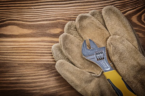 Guantes protectores llave ajustable sobre tabla de madera constructio —  Fotos de Stock