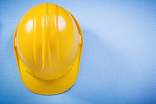 Жовтий будівельний шолом на синій поверхні концепції будівництва — стокове фото