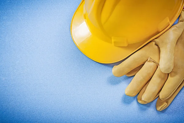 Amarelo chapéu duro luvas de segurança no fundo azul construção co — Fotografia de Stock