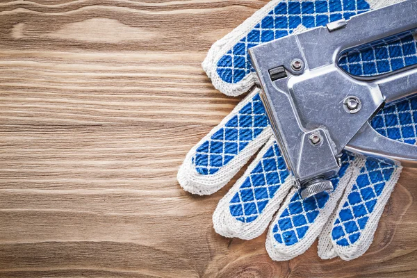 Composición de la pistola de grapas guantes de seguridad de trabajo en tablero de madera — Foto de Stock