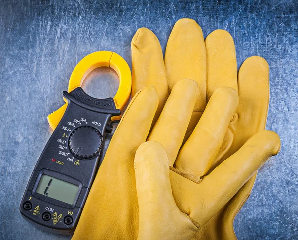 Digitale Amperemeter-Schutzhandschuhe auf metallischem Hintergrund — Stockfoto