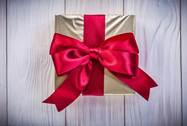 Giftbox in glittery paper with red bow on wood board holidays co — Stock Photo, Image