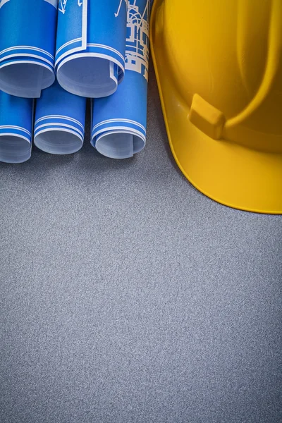 Capacete de construção azul enrolou desenhos de construção em bac cinza — Fotografia de Stock