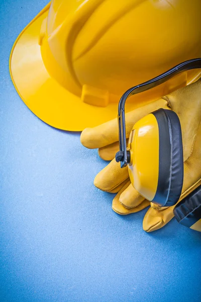 Auriculares luvas de proteção edifício capacete no fundo azul co — Fotografia de Stock