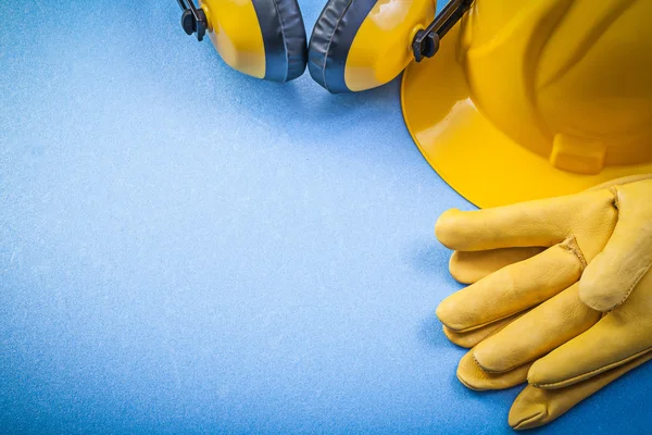 Вушні муфти шкіряні рукавички безпеки будівельний шолом на синьому фоні — стокове фото