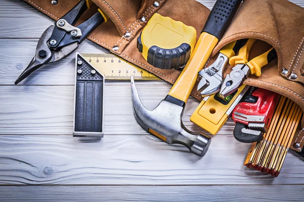 Cinto de ferramentas de couro com ferramentas de construção na placa de madeira principal — Fotografia de Stock