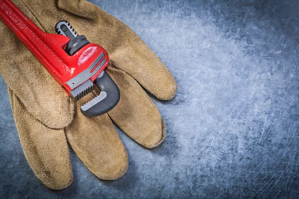 Monkey wrench protective gloves on scratched metallic background — Stock Photo, Image