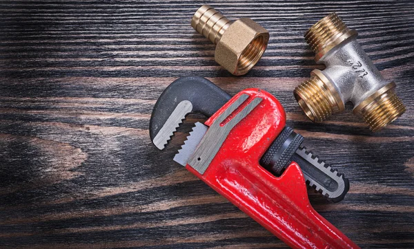 Pipe wrench brass equal tee nipple hose connector on wooden back — Stock Photo, Image