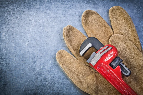 Pipe wrench safety gloves on scratched metallic background — Stock Photo, Image