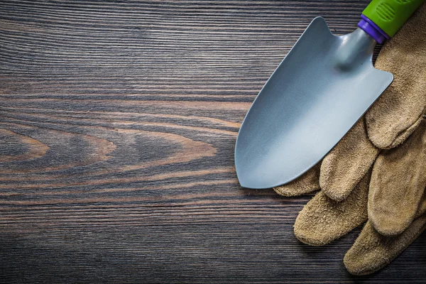 Trowel pair of leather safety gloves on wooden board directly ab — Stock Photo, Image