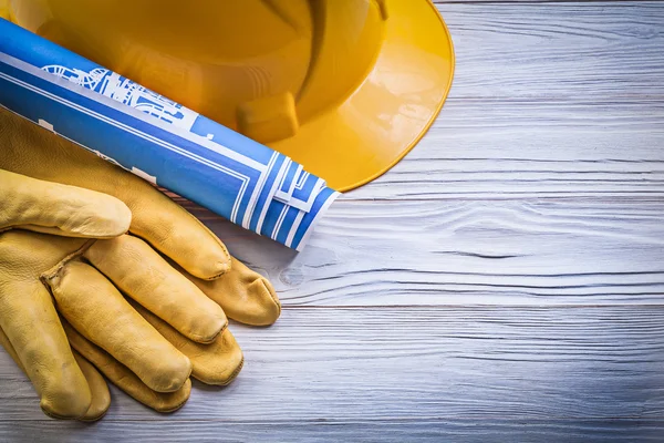 Guantes de seguridad sombrero duro dibujos de ingeniería azul en tablero de madera —  Fotos de Stock