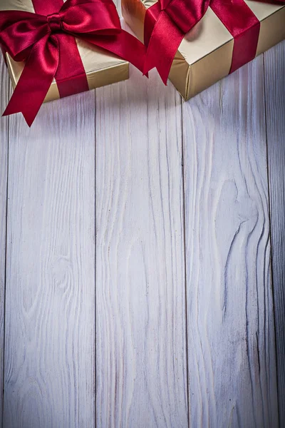 Golden gift boxes with tied bows on wooden board holidays concep — Stock Photo, Image