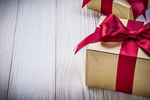 Golden present boxes with tied bows on wooden board holidays con — Stock Photo, Image