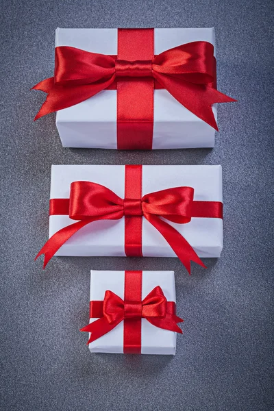 Κουτιά δώρου, σε ολόλευκο με κόκκινο δεμένα κορδέλες σε γκρι επιφάνεια αργίες — Φωτογραφία Αρχείου