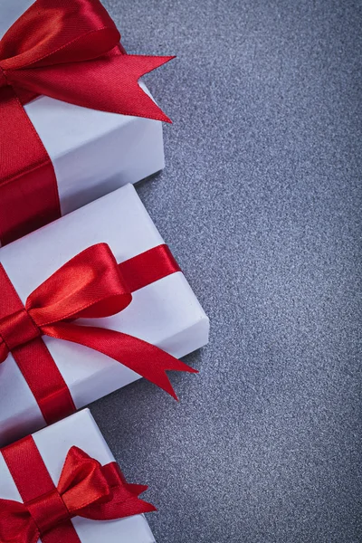 Gri yüzey tatil kavramı üzerinde bağlı kırmızı yay ile kutulu hediyeler — Stok fotoğraf