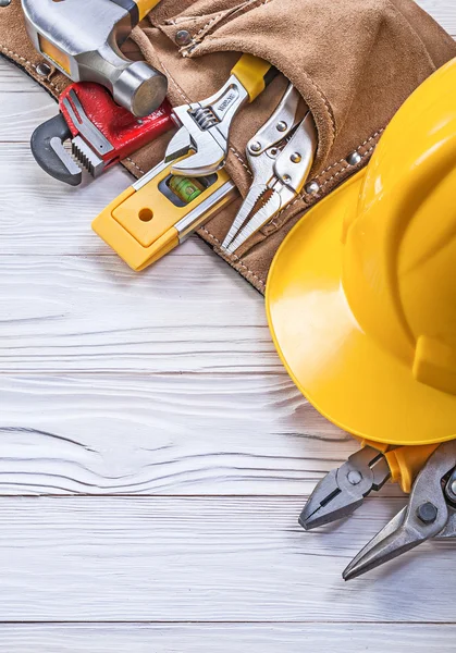 Chapeau dur de ceinture de construction en cuir sur l'entretien du panneau en bois c — Photo