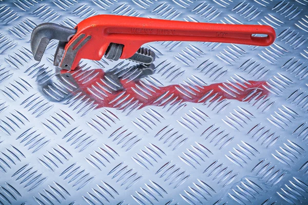 Metal pipe wrench on corrugated metallic background directly abo — Stock Photo, Image