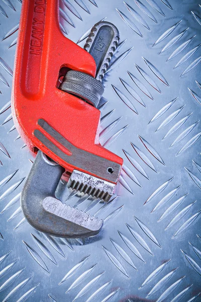 Red adjustable monkey wrench on corrugated metallic background c — Stock Photo, Image