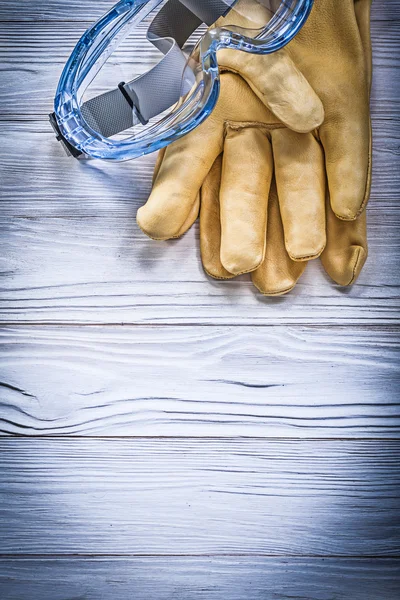 Transparent goggles protective leather gloves on wooden board co — Stock Photo, Image