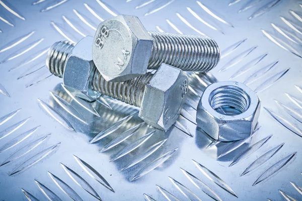 Screwbolts and construction nuts on grooved metal plate top view — Stock Photo, Image
