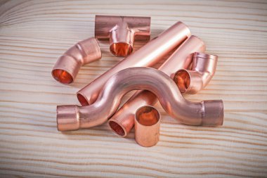 Copper pipe fittings on wooden board plumbing concept clipart