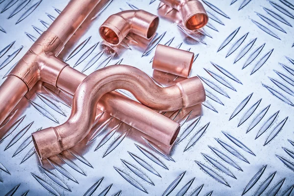 Copper pipe fixtures on corrugated metal sheet plumbing concept — Stock Photo, Image