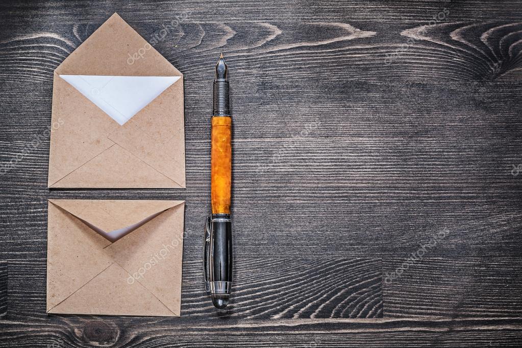 Collection of vintage post envelopes and fountain pen on wooden board copyspace.