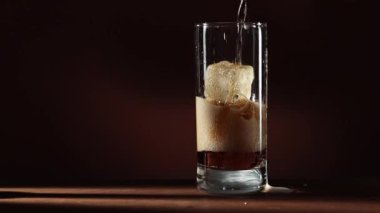 Kola, uzun şeffaf bardaklara buz küpleriyle doluyor.