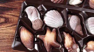 Dolly 'nin fotoğrafını çek. Kamera şeker kutusunun yanında yavaşça hareket ediyor. Tahta arka planda çikolatalı şekerler var..