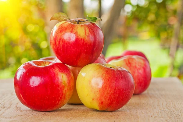 Small stack of apples on wooden table in garden — Stock Photo, Image