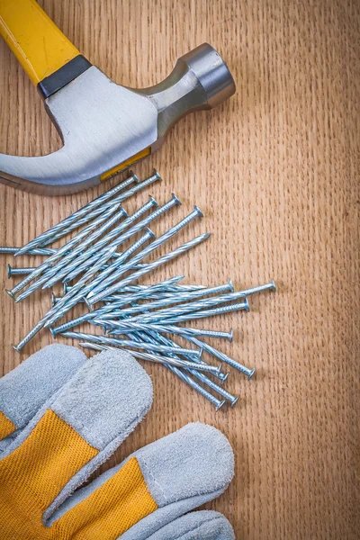 Composition of claw hammer nails and protective glove on wooden — Stock Photo, Image