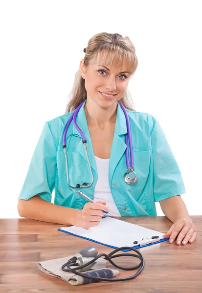 Vackra leende kvinnliga läkare sitter vid bordet handstilen och Stockbild