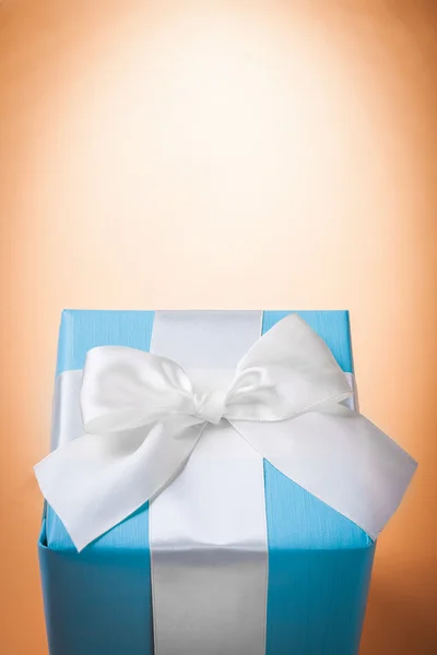 Caixa de presente azul com arco branco no fundo marrom claro com cópias — Fotografia de Stock