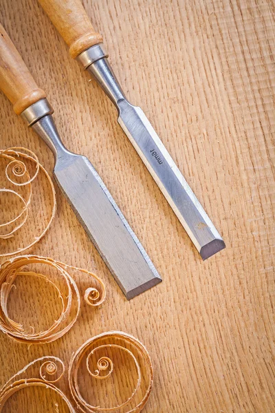 Carpentery chisels on wooden board with wooden shavings — Stock Photo, Image