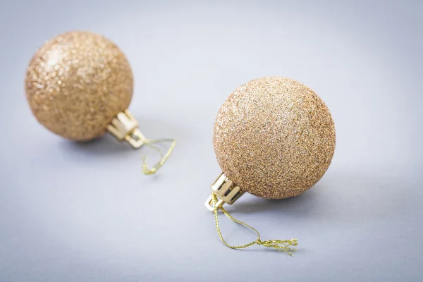 Two gld colored christmas baubles on gray background — Stock Photo, Image