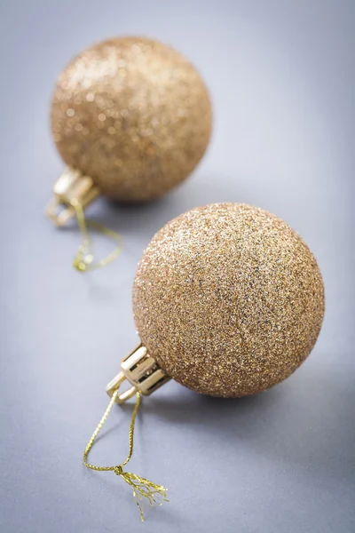 Two gold colored christmas balls on gray background — Stock Photo, Image