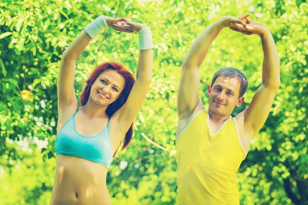 Sportsman and sportswoman exercising in park — Stock Photo, Image