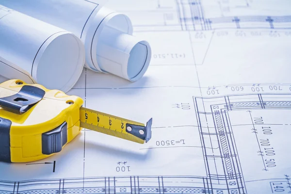 Yellow tapeline and rolls of blueprints — Stock Photo, Image
