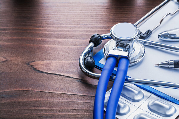 Blue stethoscope and pills in pack clipboard