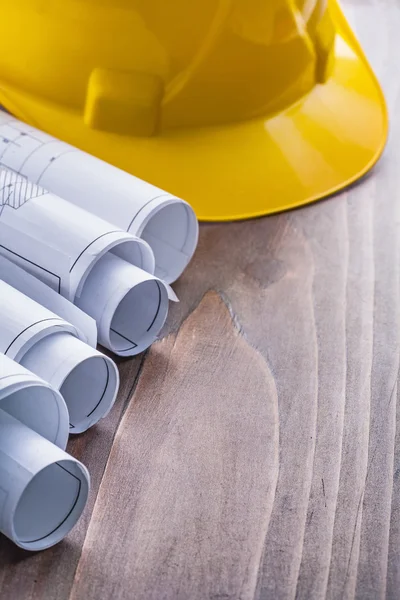 Row of rolls blueprints and construction helmet — Stock Photo, Image