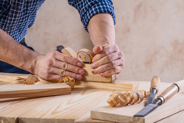 Hands of carpenter with woodworkers plane