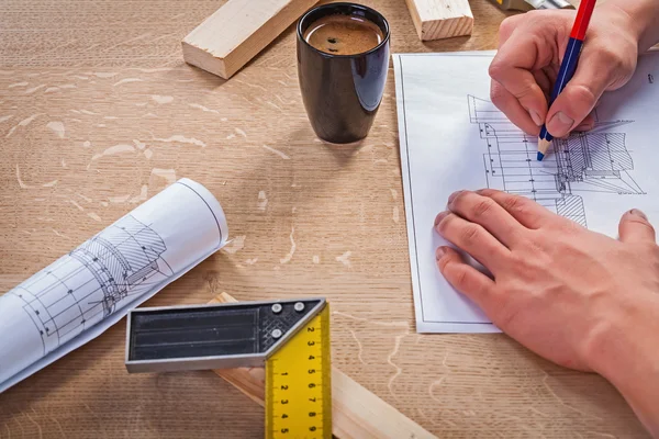 Hands of carpenter on table with blueprint and coffee — Stock Photo, Image